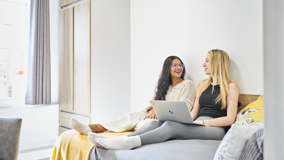 Two students sitting with their feet up on the bed and chatting 